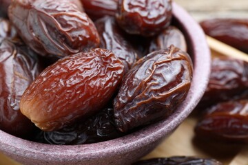 Many tasty dried dates in bowl on table, closeup