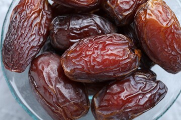 Many tasty dried dates in bowl on table, top view