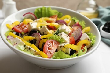 Delicious fresh Greek salad in bowl on white table, closeup
