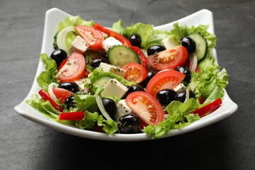 Delicious fresh Greek salad on black table, closeup