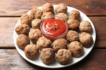 Delicious meatballs with ketchup and spices on wooden table, closeup