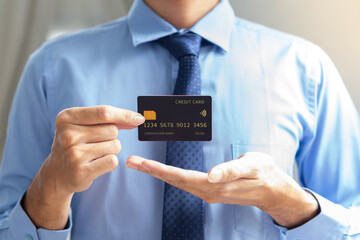 business man with blue suits and necktie showing mockup black credit card with blurry background