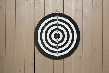 One dart board hanging on wooden background