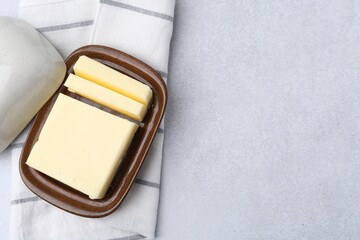 Cut tasty butter in dish on light grey table, top view. Space for text