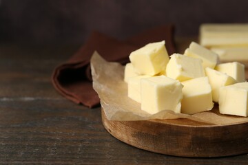 Pieces of fresh butter on wooden table, closeup. Space for text