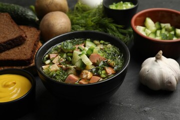 Delicious okroshka soup with kvass and ingredients on black table, closeup