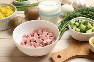 Fresh ingredients for okroshka soup on light wooden table, closeup