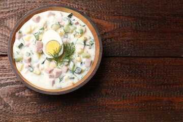 Delicious okroshka soup with kefir in bowl on wooden table, top view. Space for text