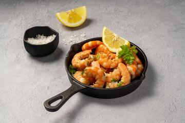Cooked red prawn with spices in a pan, served with fresh herbs and lemon