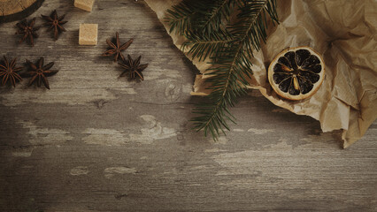 Christmas flat lay. Spruce twigs, star anise, dried orange slices, brown sugar, crumpled baking paper on a wooden background, copy space.