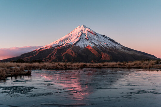 Mont Taranaki au lever du soleil se refl&eacute;tant dans son lac gel&eacute; - Nouvelle Zelande