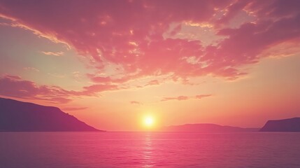 Fototapeta premium Soft sunset light over water with pink clouds and dark mountains in a calm landscape