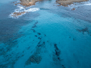 Aerial view of mediterran seafloor and coastline with waves and spray in Italy.