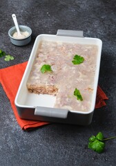Cold appetizer, meat jelly or aspic  with turkey and pork in a rectangular ceramic form on a dark...