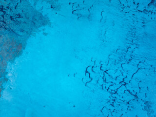 Aerial view of shallow turquoise ocean water with seafloor underneath. Overhead view of mediterran sea.