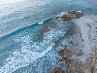 Aerial view ocean waves on remote and wild sandy beach in Italy. Background texture of water, waves and beach.