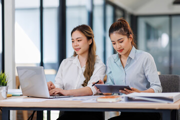 Asian Business women using calculator and laptop for doing math finance on an office desk, tax, report, accounting, statistics, and analytical research concept
