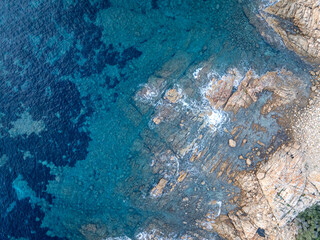 Aerial view of mediterran seafloor and coastline with waves and spray in Italy.