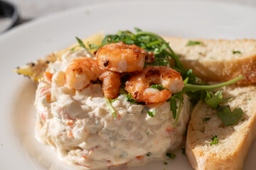 plate of 'ensaladilla rusa' (russian salad) made of potatoes, shrimps, egg, onion and mayonnaise - a typical spanish snack or tapas