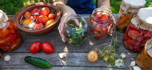 woman canning tomatoes cucumbers vegetables on the background of nature