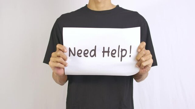 a footage of a man holding a piece of paper with need help written on it