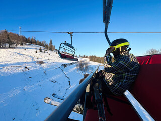 Ski enthusiast relaxing on a chairlift in scenic snowy mountain terrain