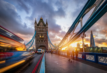 Obraz premium Sunset view of the Tower Bridge in London, England, with tourists strolling down the street and blurred car traffic