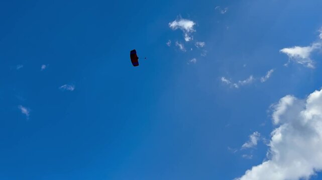 Parachutists fly on background of a blue sky with clouds, parachutists are paragliding. Skydiving in clear weather. Single, Self jumps. Extreme sport. Tandem jumping