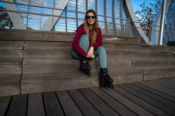 Young sporty woman wearing inline skates sitting and relaxing on wooden steps