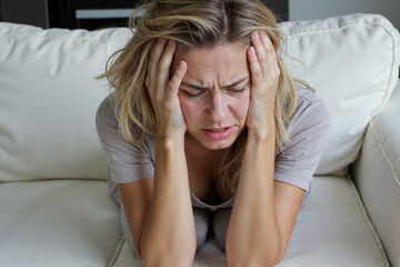 Fototapeta premium Headache, migraine attack. Girl sitting on the couch with a headache.
