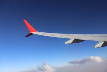 Fototapeta premium Traveling by plane - from the window of a passenger aircraft, the wing of an airplane. The concept of vacation, travel, logistics