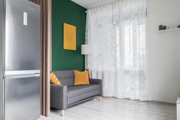 modern living room design. Green walls, grey sofa, yellow cushions, floor lamp. Close up of sofa.   Empty wall and art frame mock-up template. Modern flat. Space for relaxation. Architecture inside.