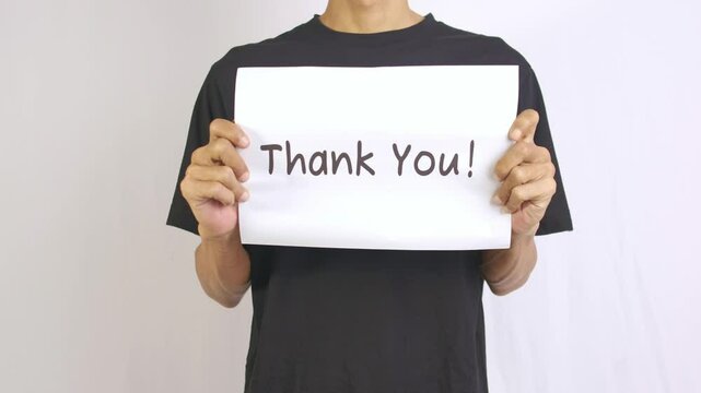 a footage of a man holding a piece of paper with thank you written on it