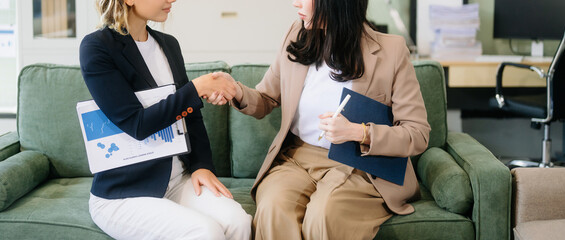 Two businesswomen collaborate using a tablet in a stylish office setting. Perfect for concepts