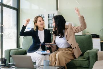 Two businesswomen collaborate using a tablet in a stylish office setting. Perfect for concepts