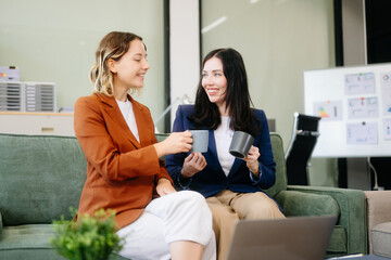 Two businesswomen collaborate using a tablet in a stylish office setting. Perfect for concepts