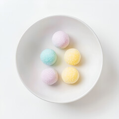 Obraz premium Pastel-colored spherical candies in a white bowl. Sweet treats, perfect for a spring or Easter theme.