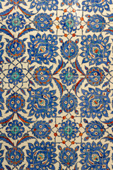 A close up of traditional Ottoman Iznik tiles featuring floral and geometric patterns in blue, red and white. This historical ceramic art reflects rich Turkish heritage