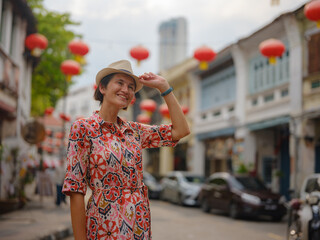 Young woman in ethnic dress and hat exploring the festive streets of George Town, Malaysia, during...