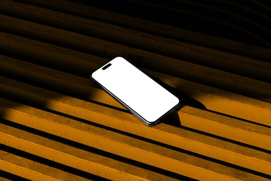Blank smartphone mobile device on a reeded wooden background mockup template in an urban outdoor environment. Isolated blank surface to place your design. 