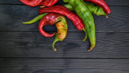 Chili red and green peppers with salt and garlic on black wooden background