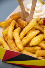 Belgian street and fast food, paper box in colors of Belgian flag with fried potato frit chips and ketchup and mayonnaise sauсe