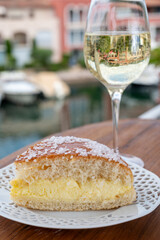 Wine and cakes of French Riviera, glasses of cold white Cote de Provence wine and Tarte Tropezienne cake in yacht harbour of Port Grimaud, summer vacation in Provence, France