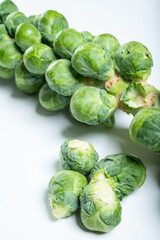 Fototapeta premium Green brussels sprouts on stalks on white table