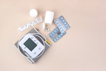 Digital blood pressure tonometer and pack of pills on a light background with copy space.