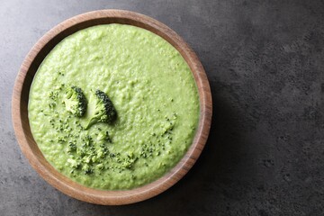 Delicious broccoli cream soup in bowl on grey table, top view. Space for text