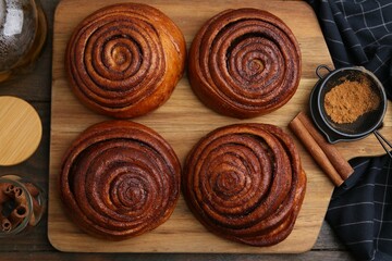 Delicious cinnamon rolls, sticks and powder on wooden table, flat lay