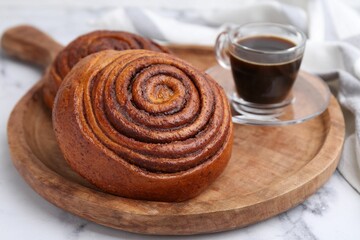 Delicious cinnamon rolls and coffee on white marble table, closeup
