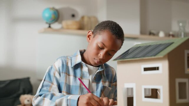 Younger brother is focused on assembling components of solar-powered house. His determination highlights how collaboration allows both siblings to take turns contributing their skills to project
