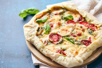 Galette-type pie made from puff pastry and filled with tomatoes, mozzarella cheese and pesto sauce. Galette Caprese